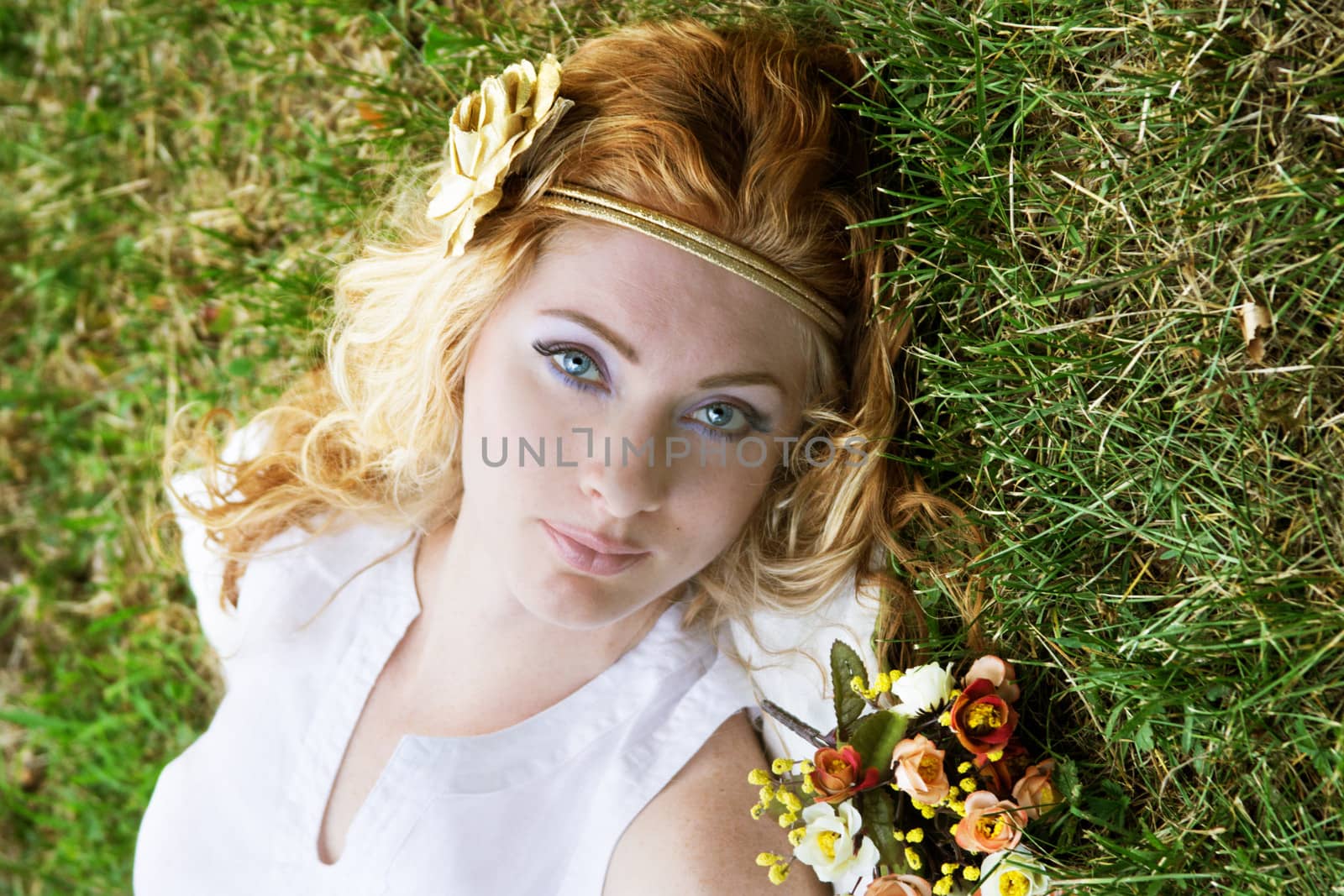 Romantic red-headed woman lying on green grass