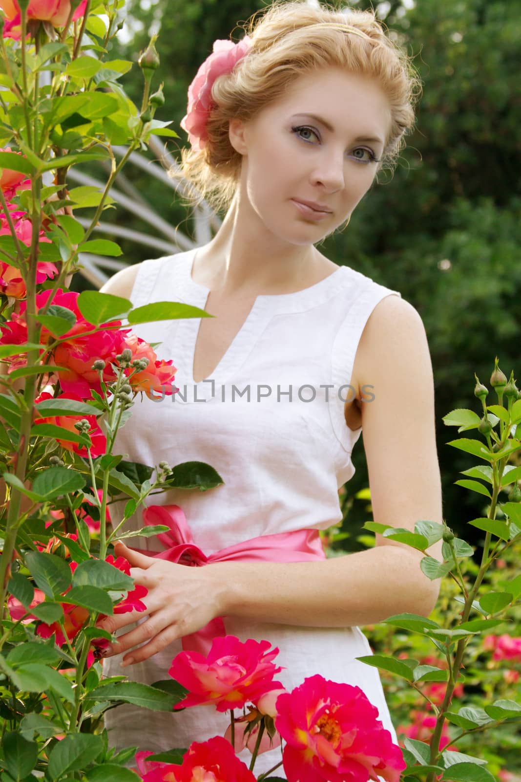 Sensual woman among pink rose garden walking