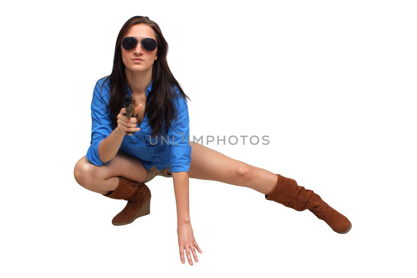 A lovely young brunette kneels, holding a modern handgun.  Isolated on a white background with generous copyspace.