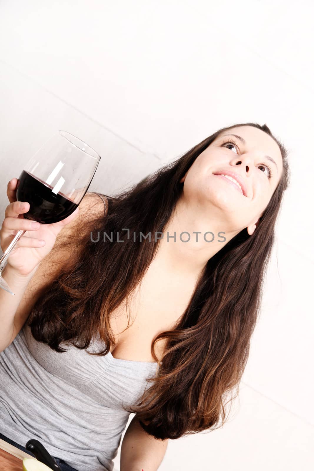 A young adult woman with fruits and wine in the kitchen.