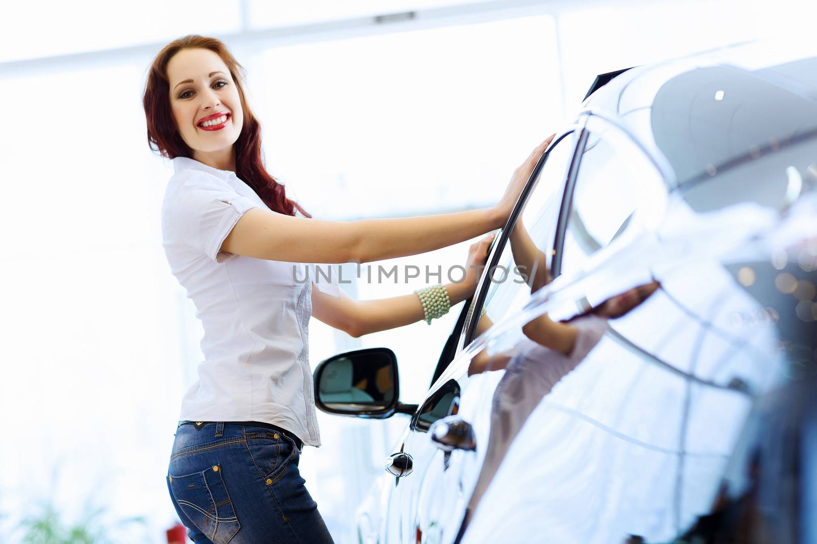 Pretty woman standing near car at car center. Choosing a car