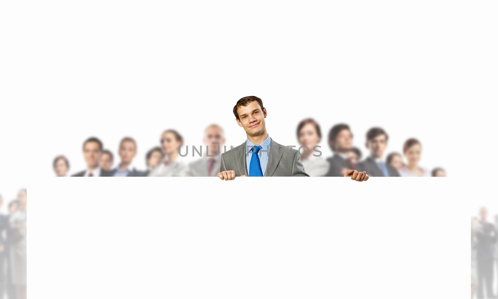 Image of young man holding blank banner with crowd of business people at background