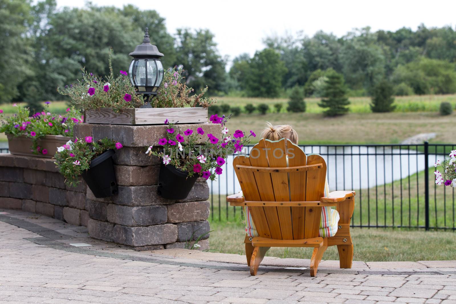 Person relaxing in a garden chair with their back to the camera overlooking open countryside and a small lake