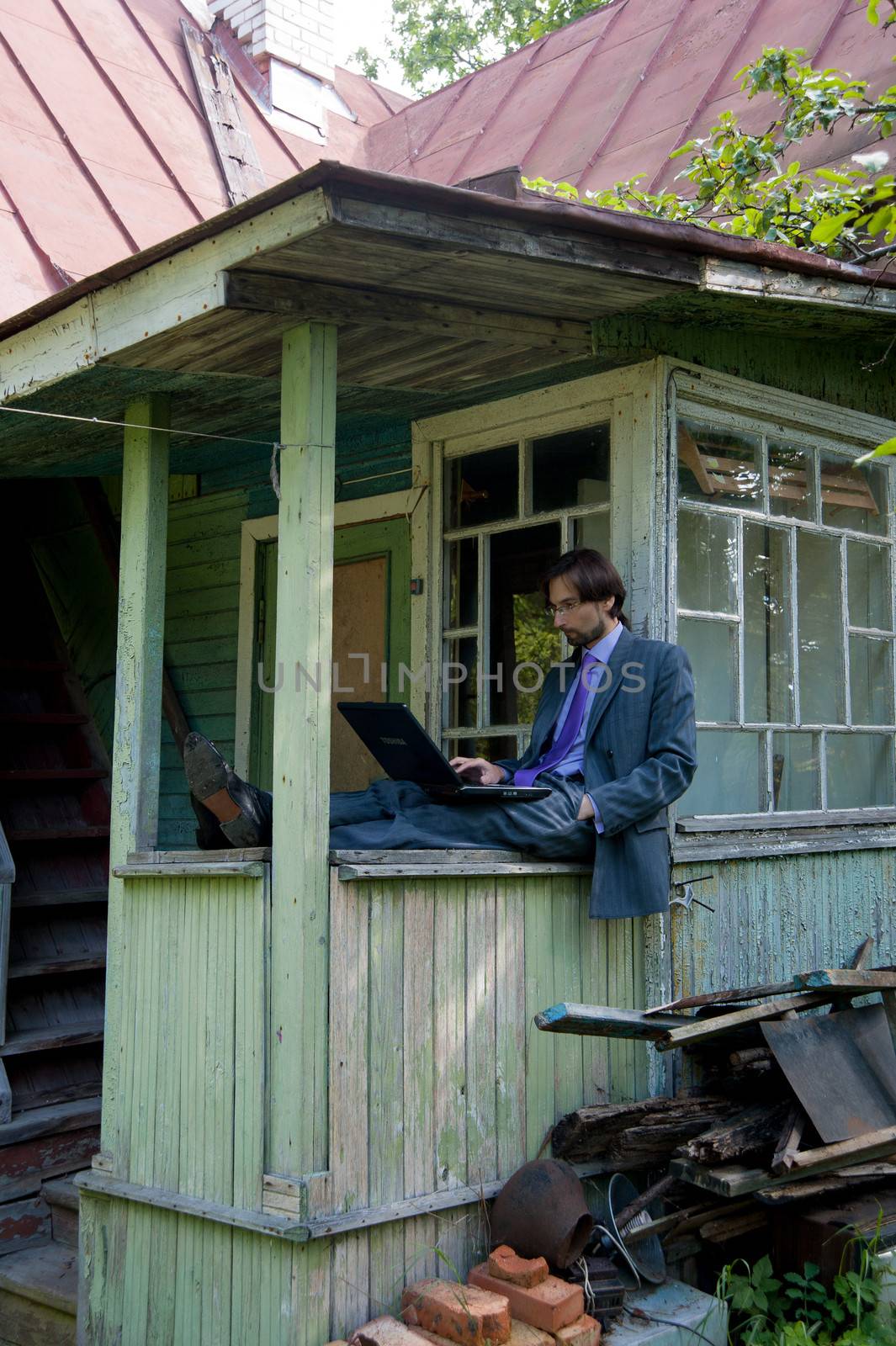 Business man using a laptop with an old village house