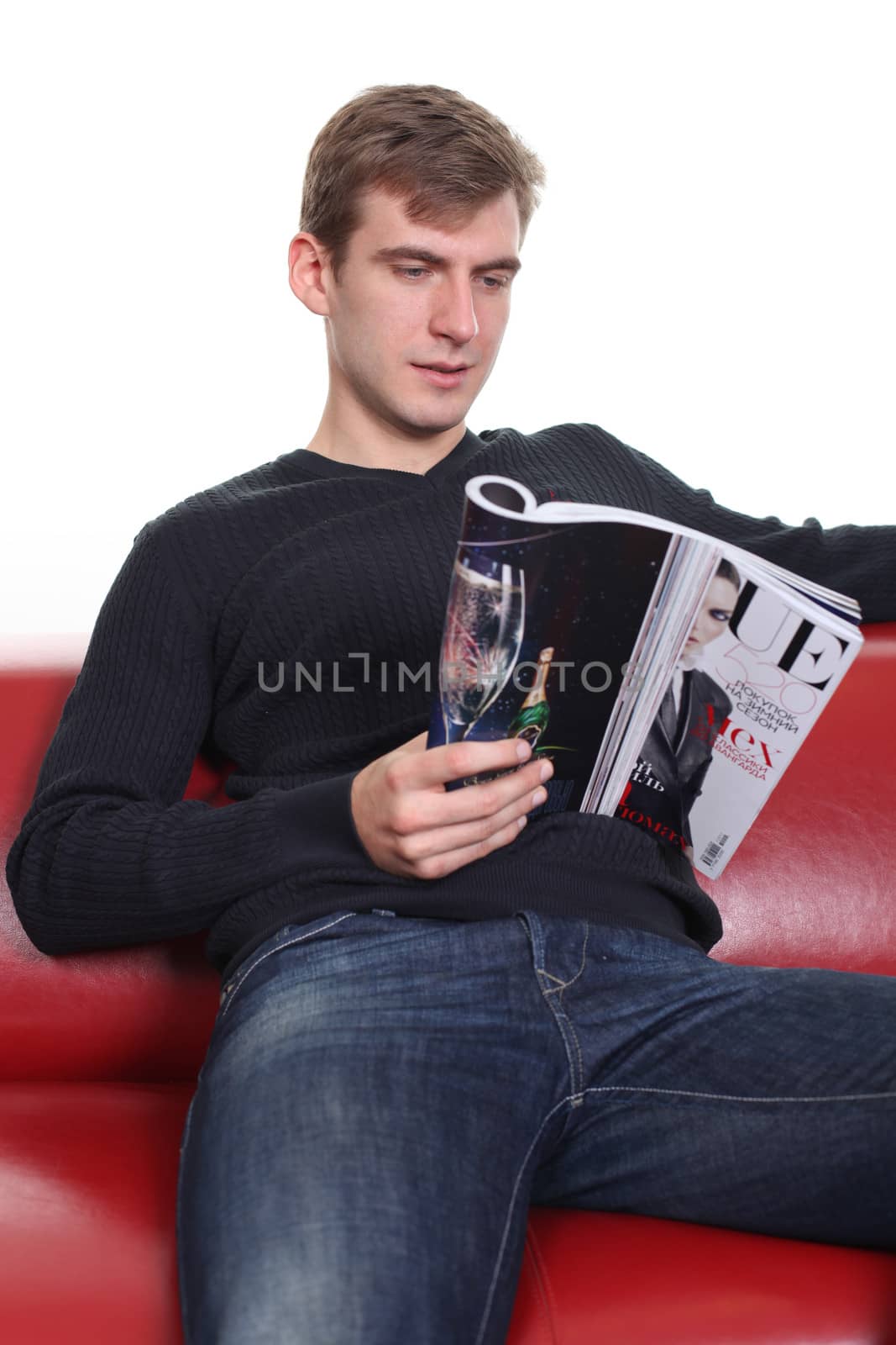 young man with magazine sitting on sofa by andersonrise