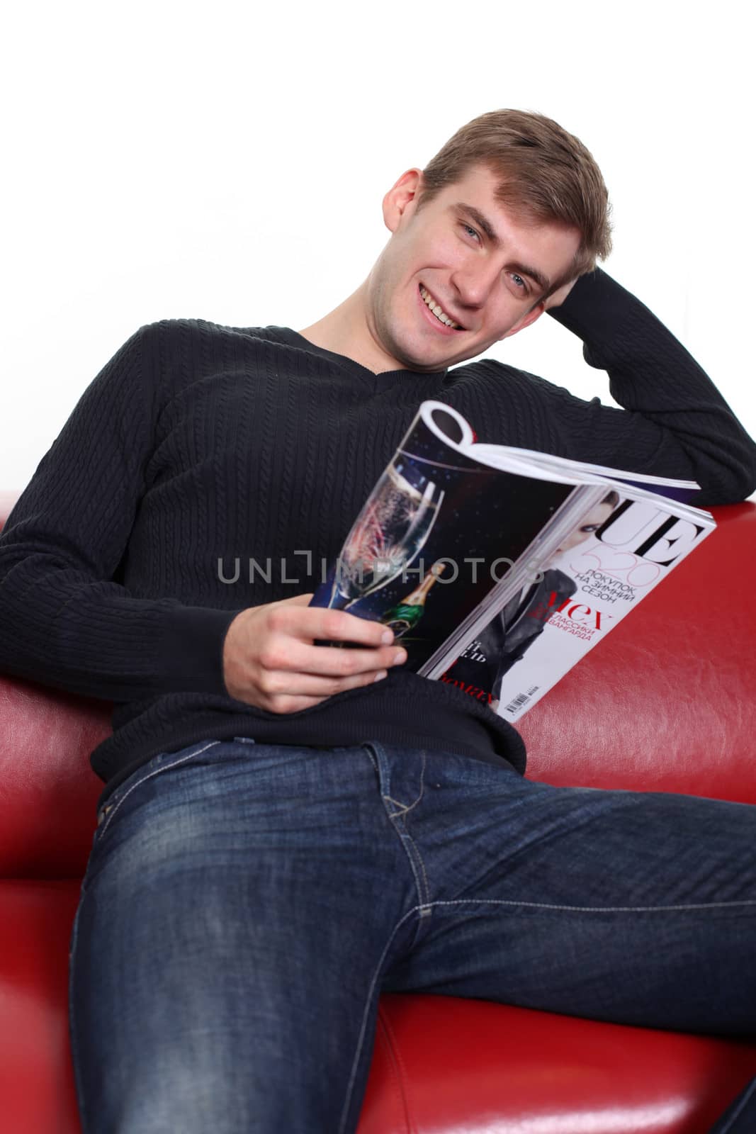 young man with magazine sitting on sofa by andersonrise