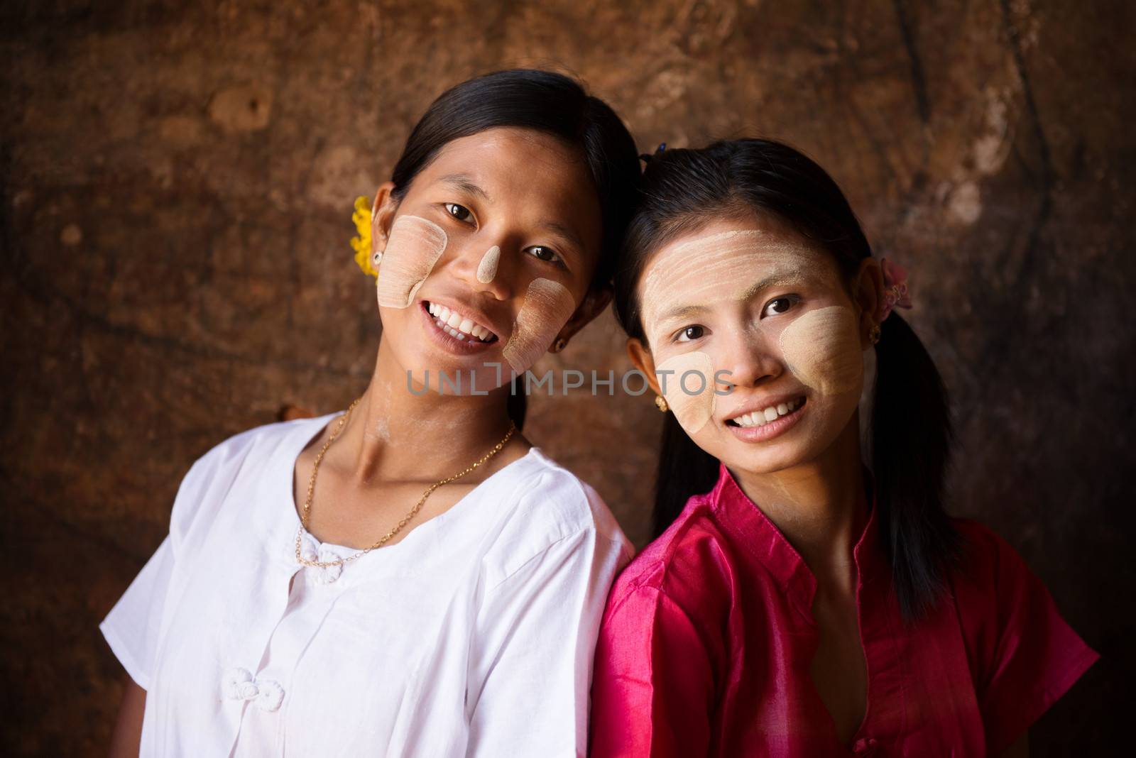 Portrait of two beautiful young traditional Myanmar girls smiling together.