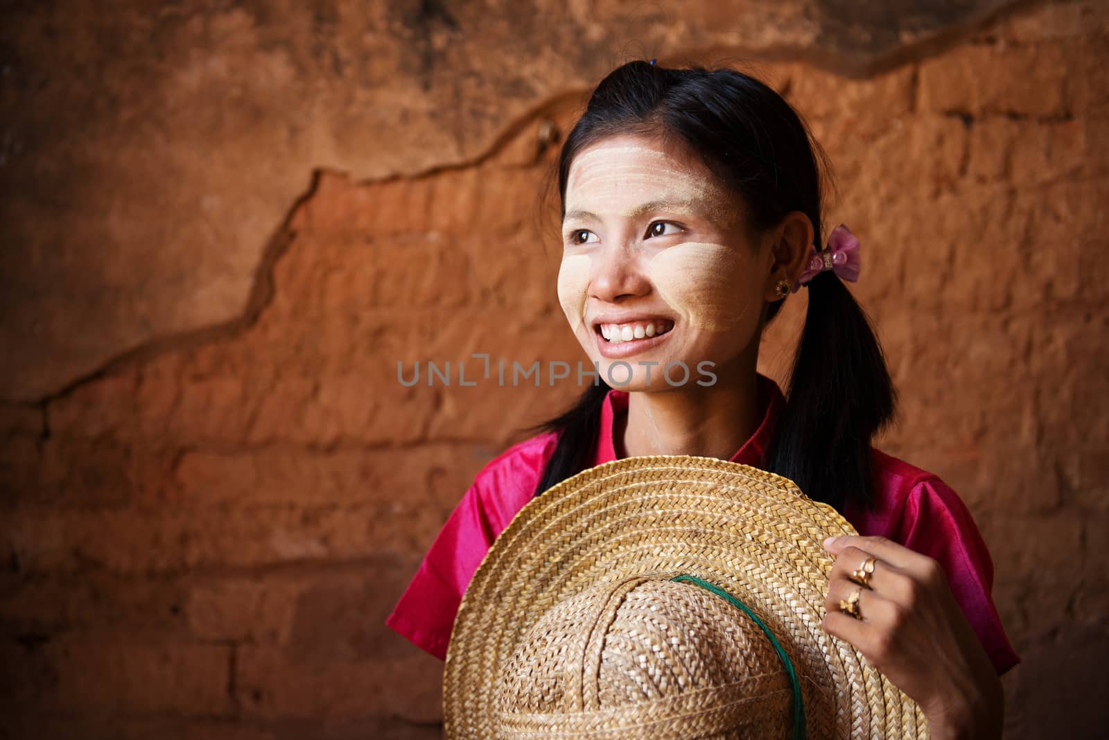 Portrait of beautiful young traditional Myanmar girl with straw hat looking away. 