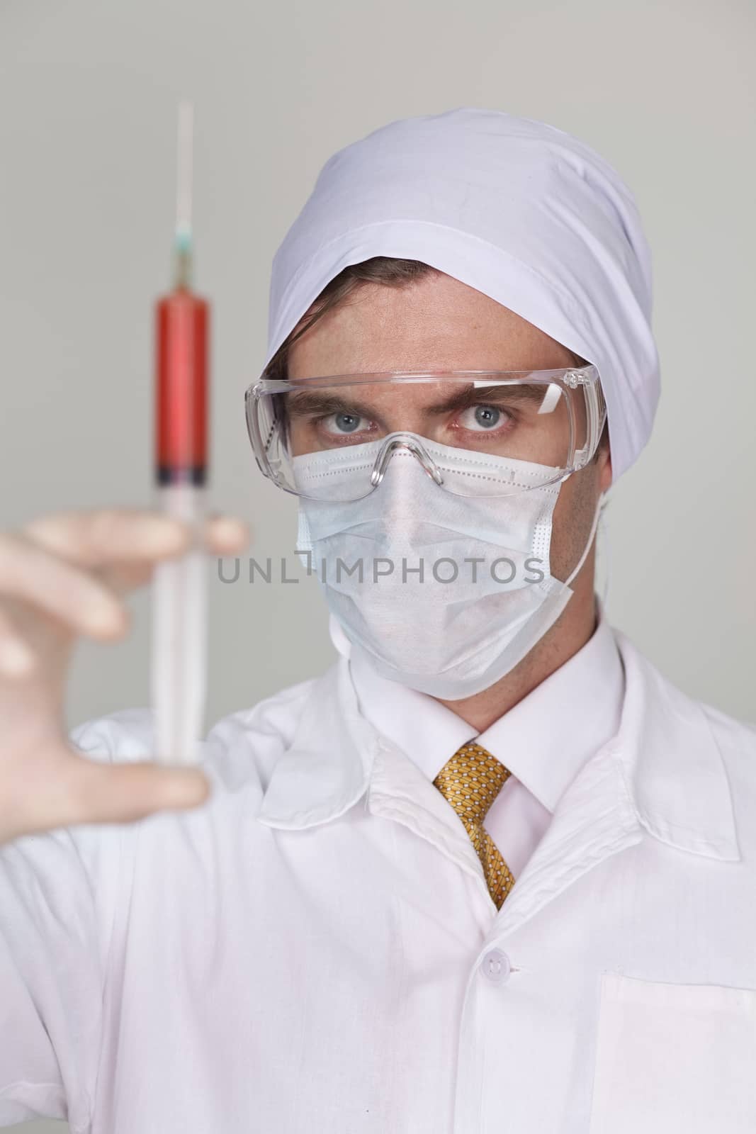 Confident surgeon holding a syringe against a white background