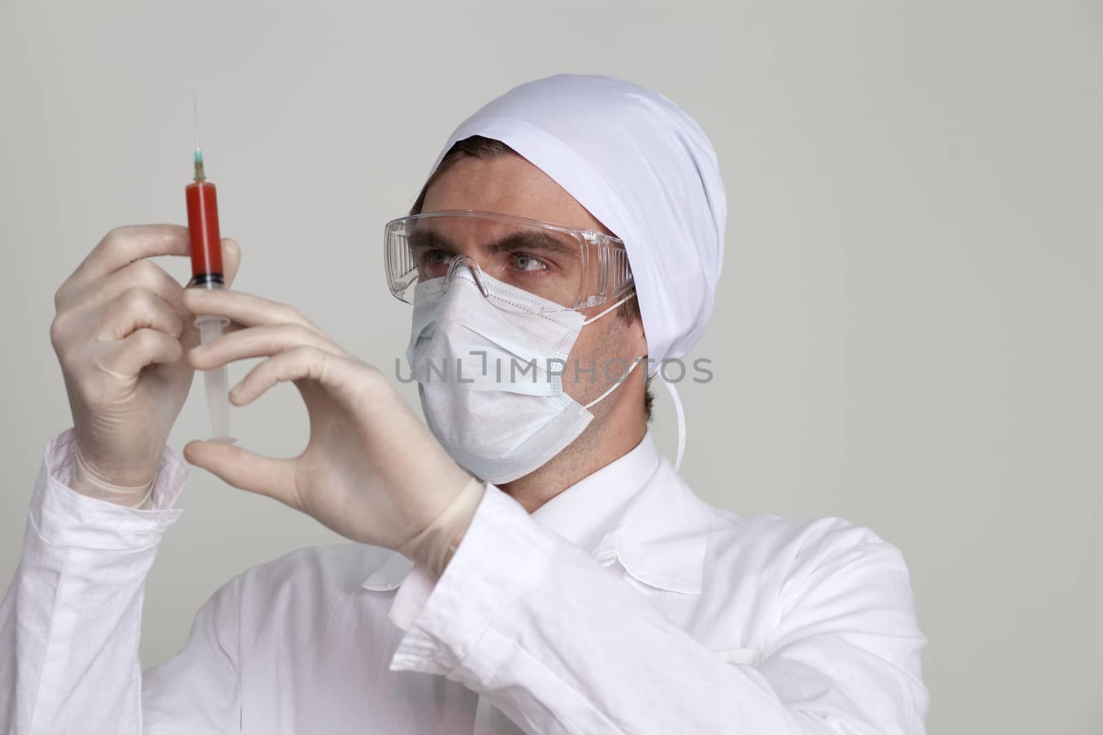 Confident surgeon holding a syringe against a white background