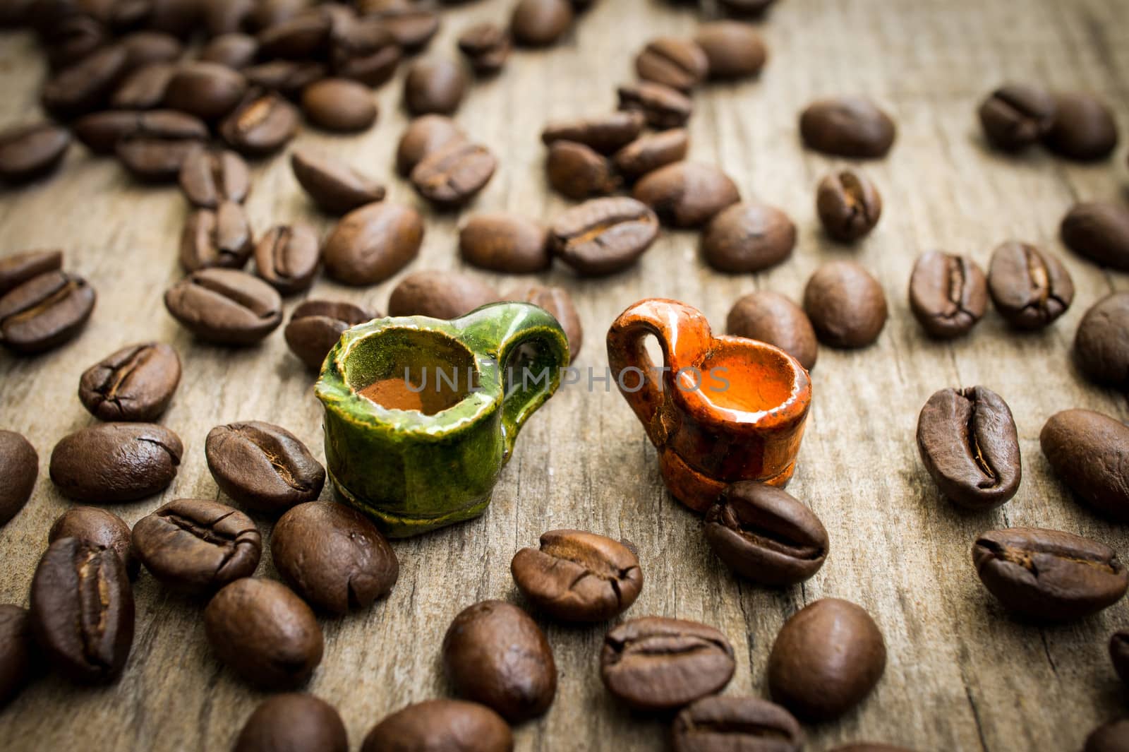 Miniature coffee cups with coffee beans on wood background