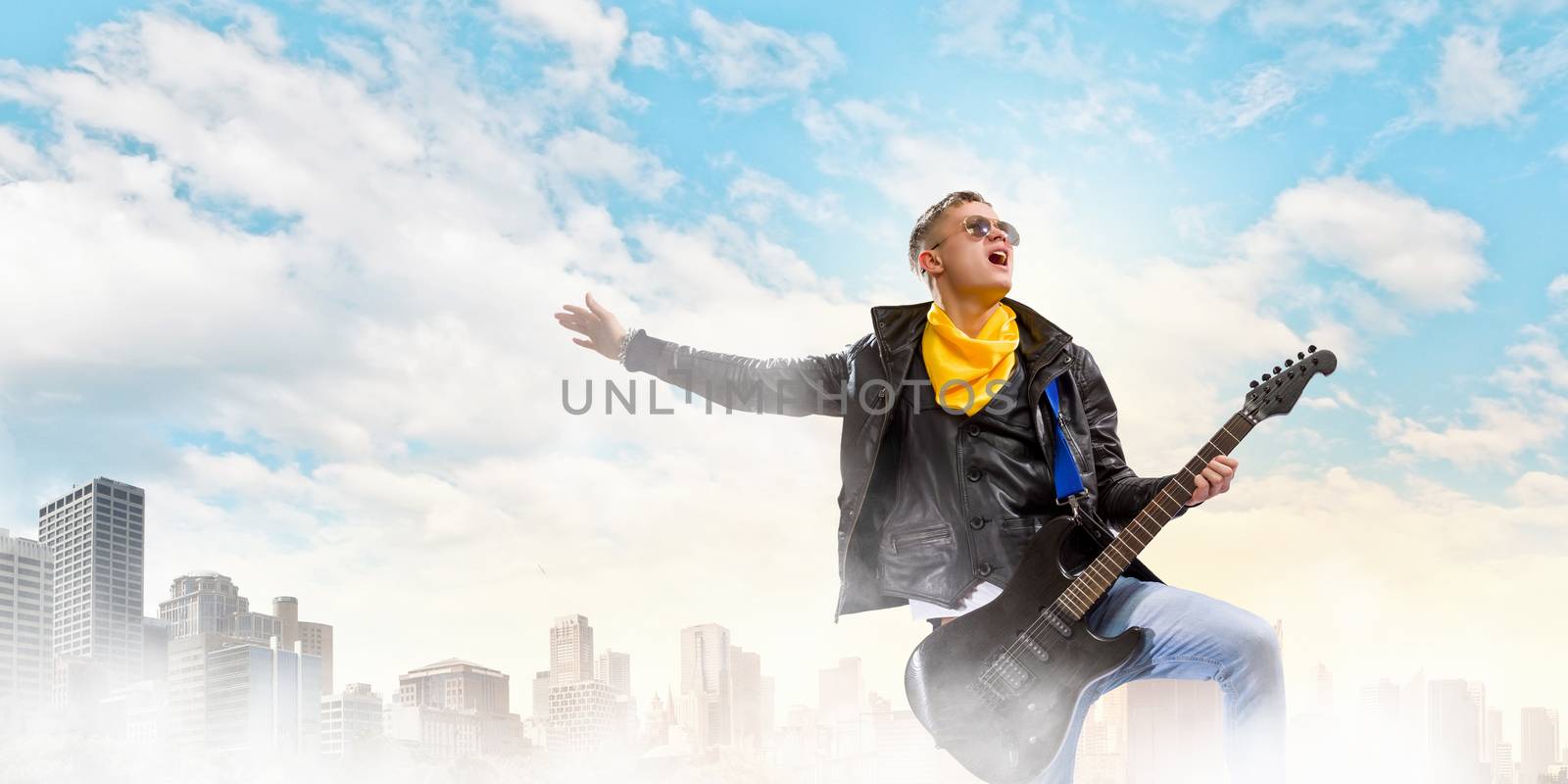 Young man, rock musician in jacket with guitar
