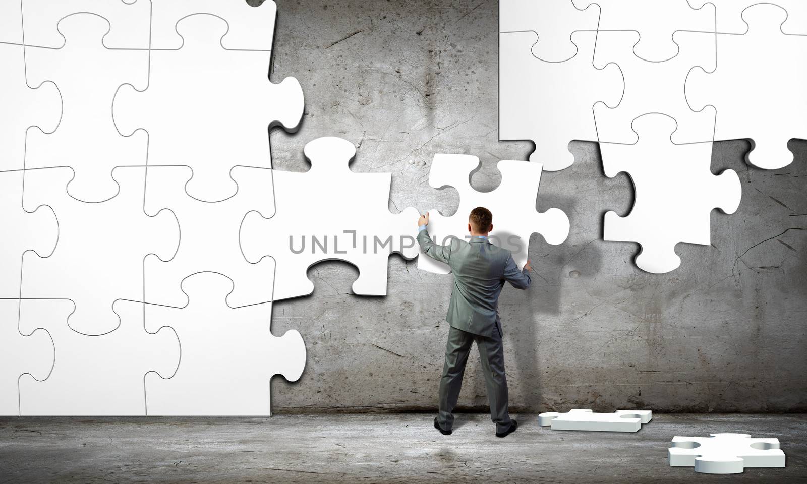 Image of businessman compiling macro white puzzle. Building business