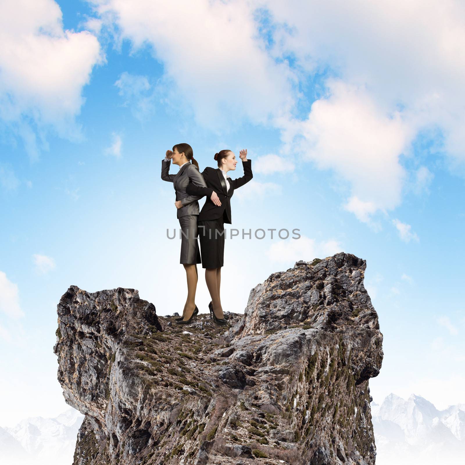 Image of two businesswomen looking into distance standing back to back