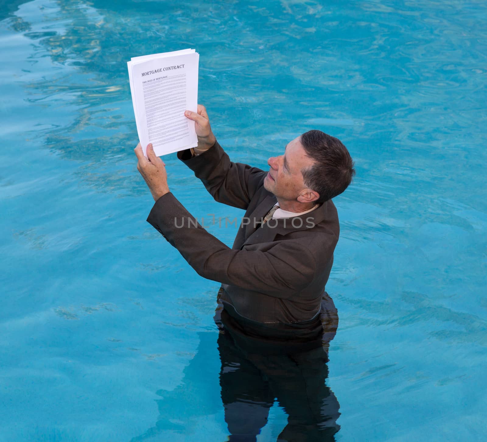 Senior caucasian businessman in suit up to waist in deep blue water worried about being underwater with mortgage payments