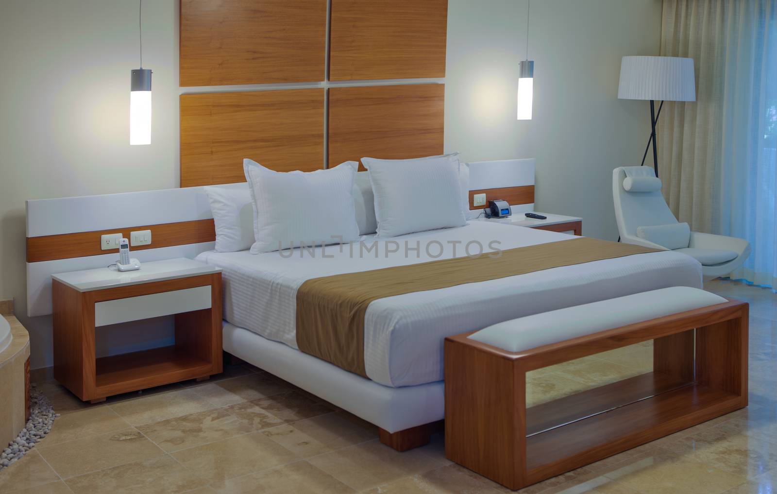 Bedroom interior in a house or hotel with minimalist decor in neutral tones and a large double bed