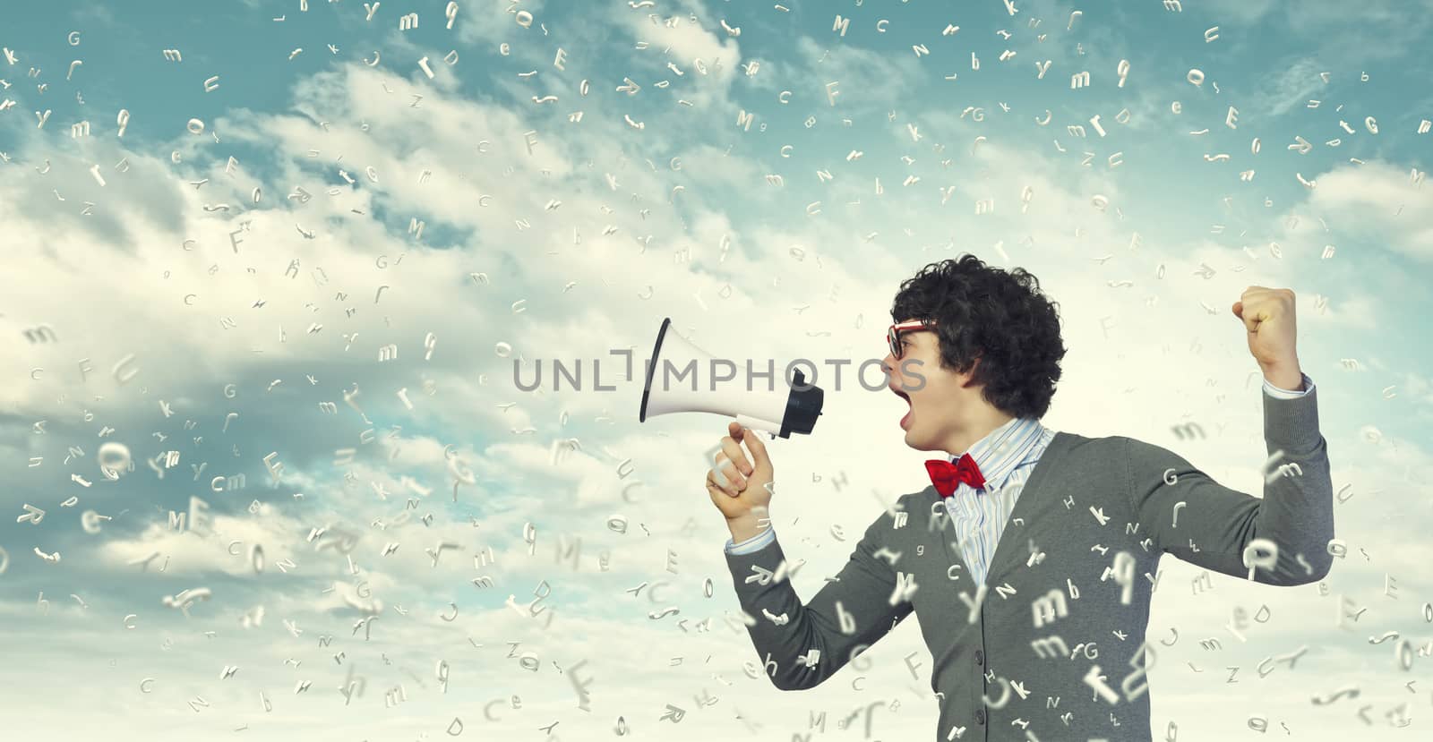 Portrait of young man shouting loudly using megaphone