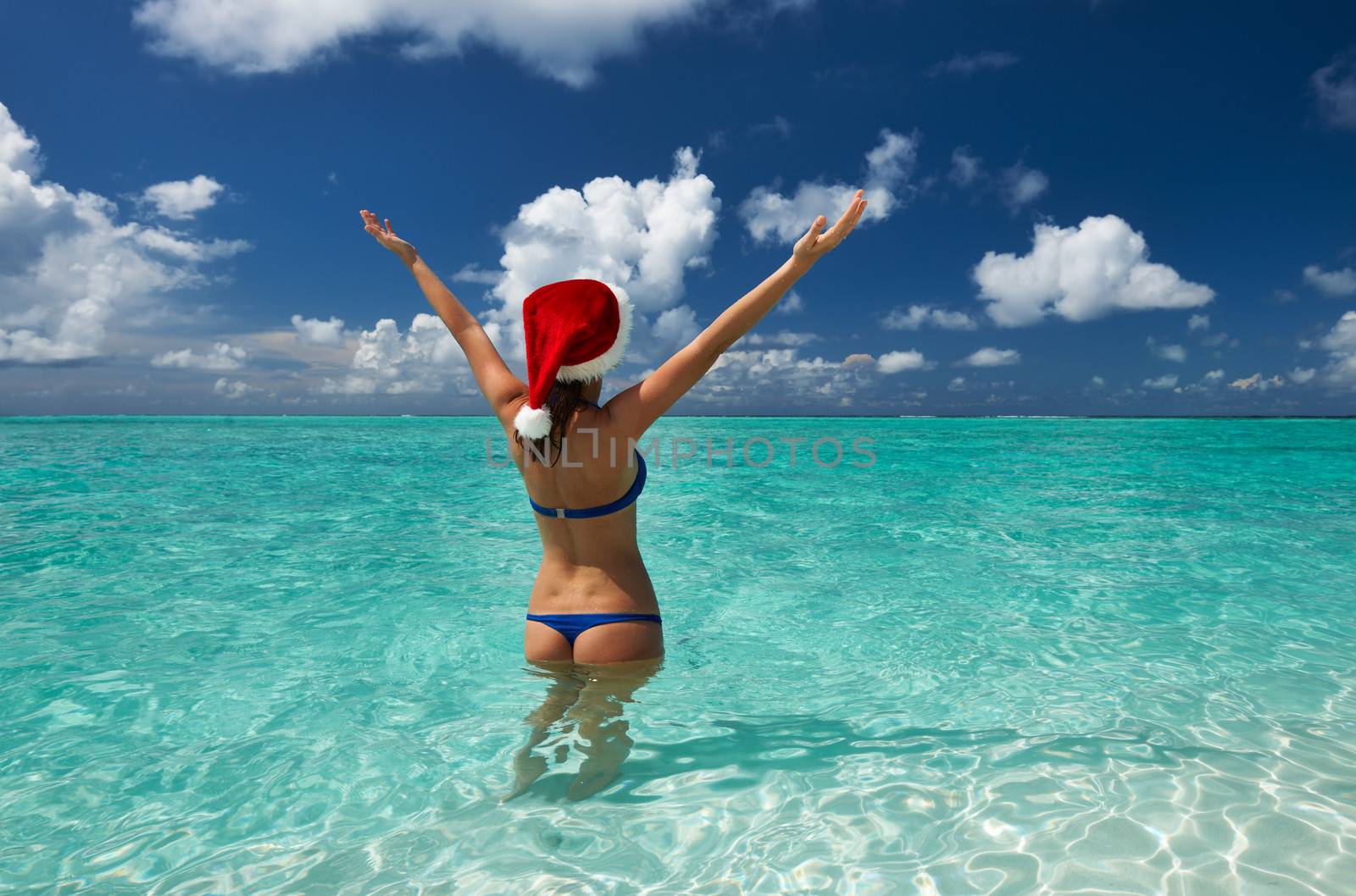 Woman in santa's hat at beach by haveseen