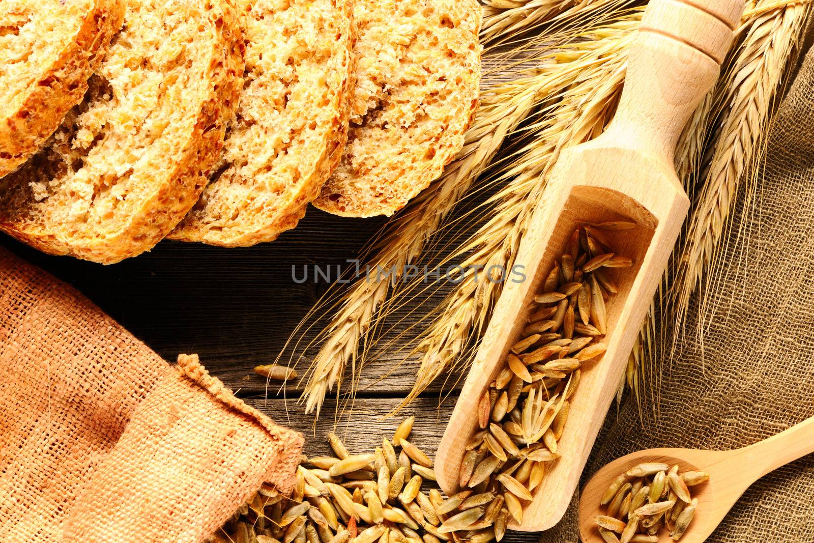 Rye spikelets and bread on wooden background