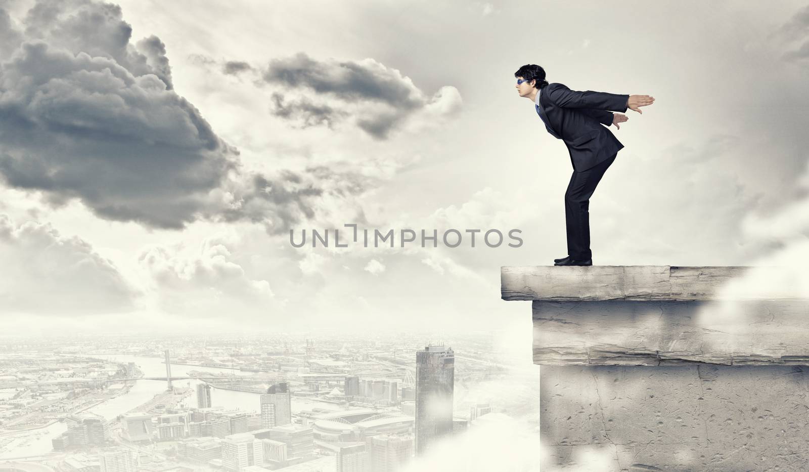 Image of young businessman in goggles jumping from top of building