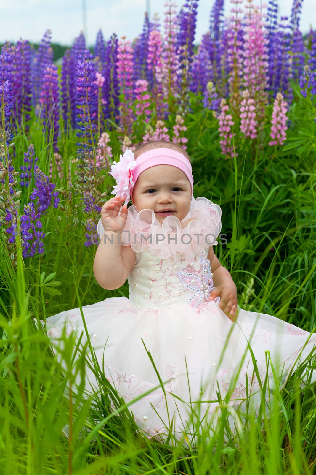 Little girl in an elegant dress sits on a grass