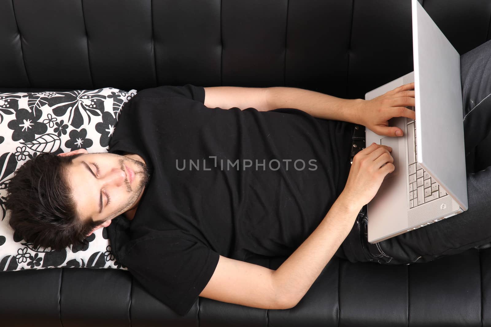 A young hispanic man with a laptop on the Sofa.