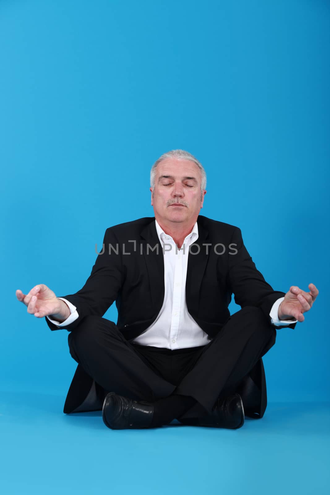 Businessman sitting in a lotus position by phovoir