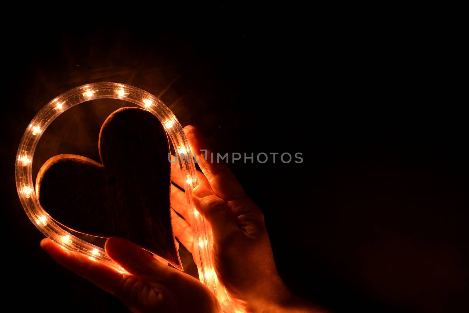 Hands holding an illuminated heart