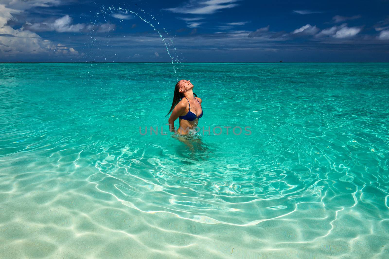 Woman splashing water with hair in the ocean by haveseen