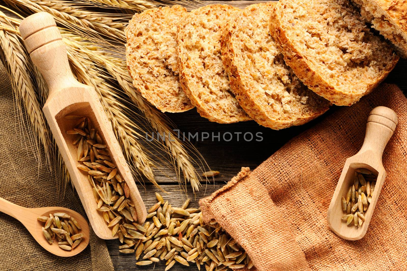 Rye spikelets and bread on wooden background