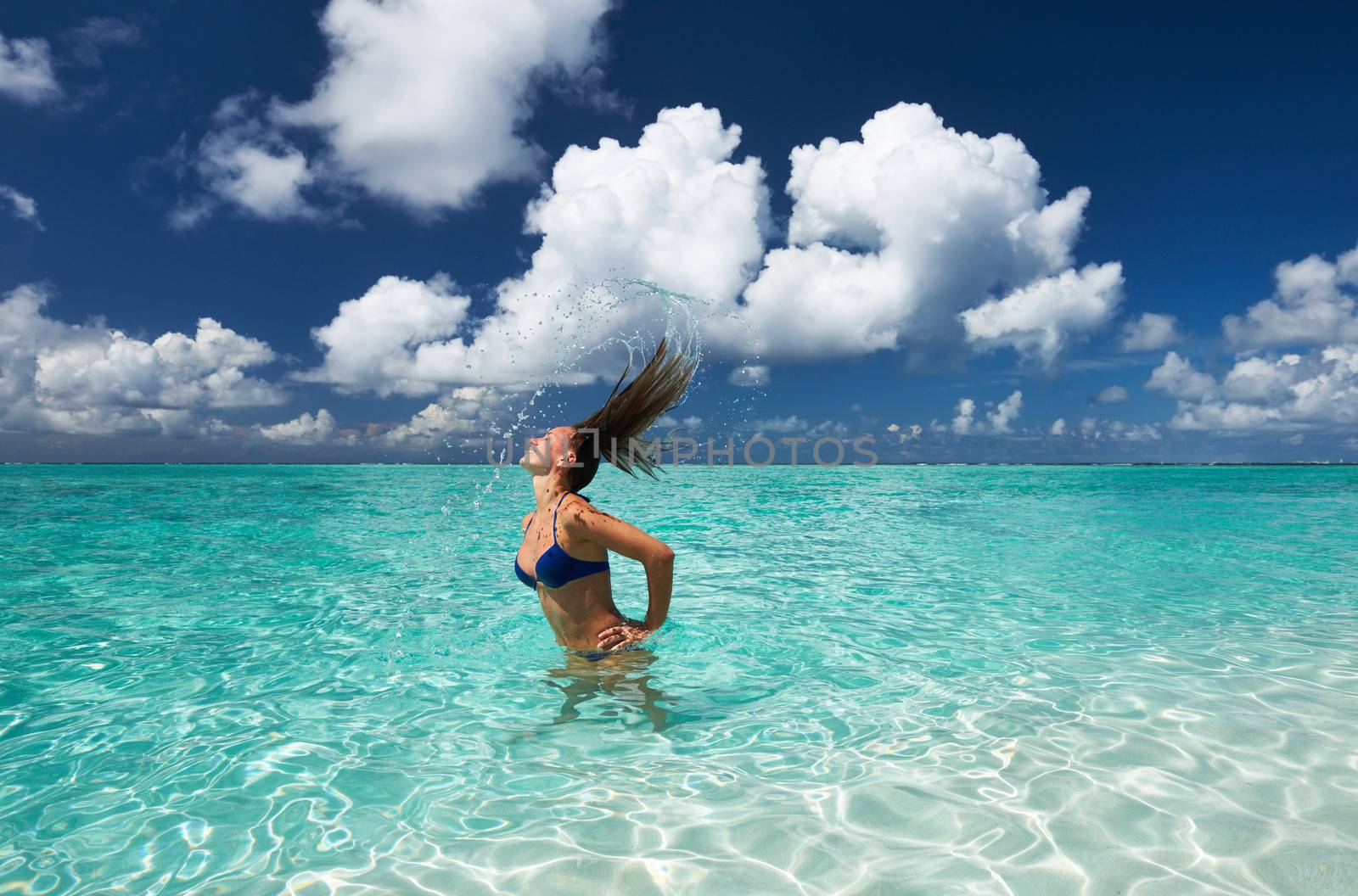 Woman splashing water with her hair in the ocean