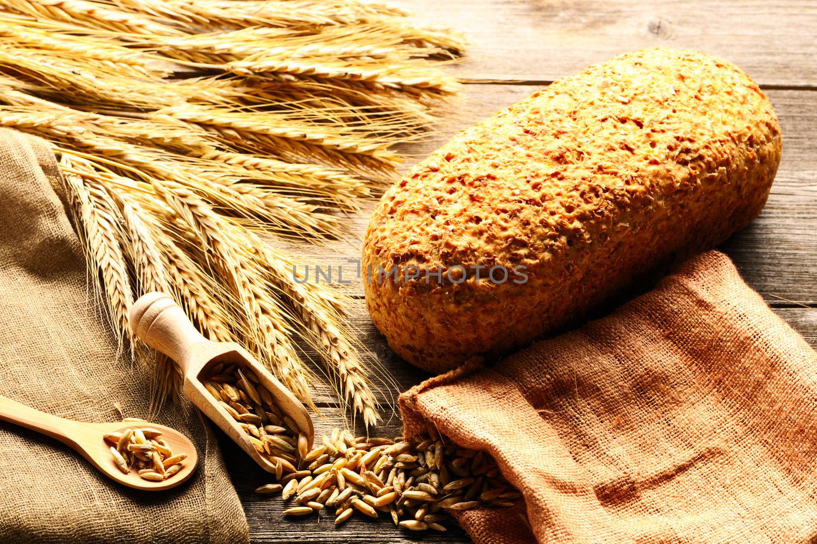 Rye spikelets and bread on wooden background