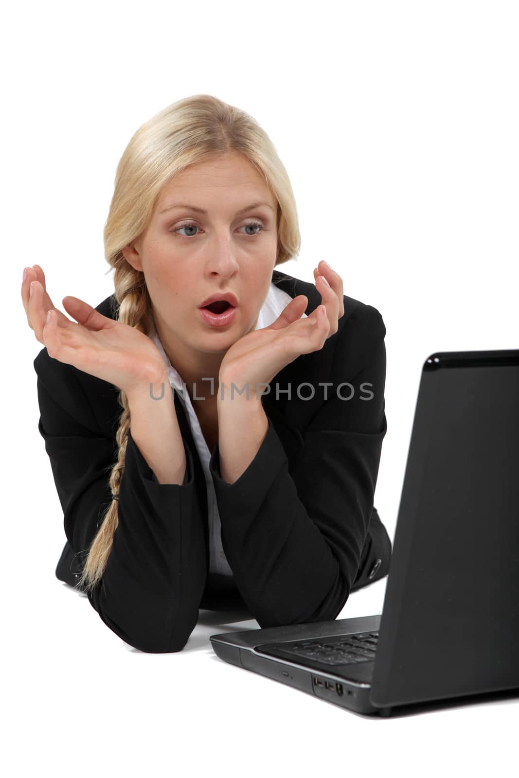 Shocked blond businesswoman sat in front of laptop by phovoir