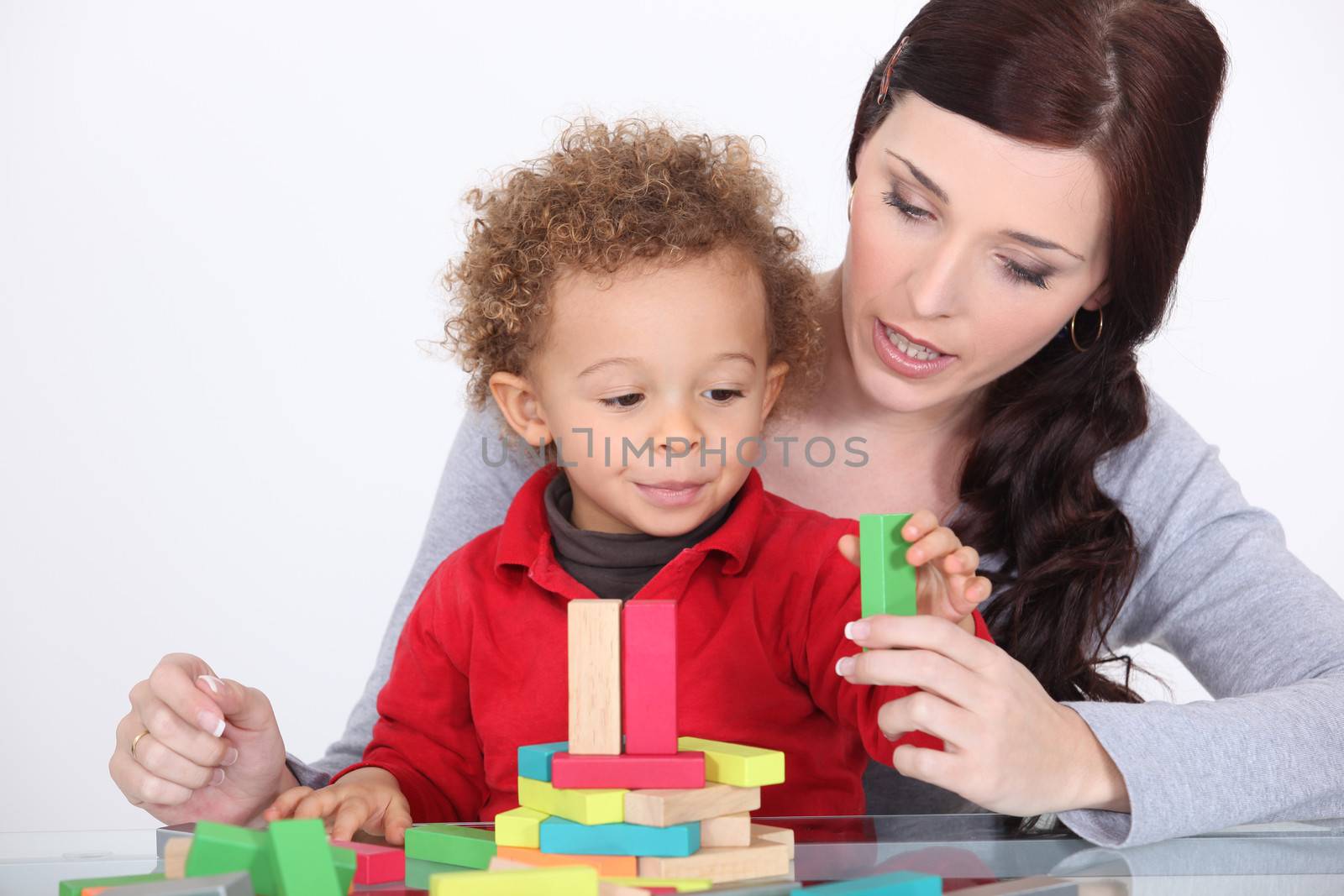 young mother and little son playing with construction set by phovoir