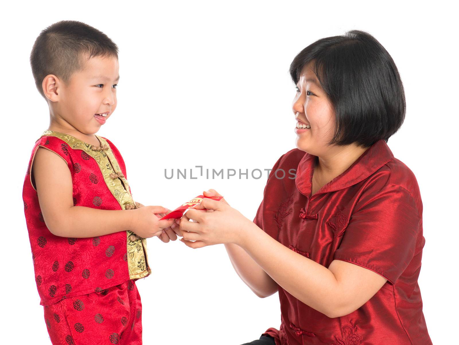Asian Chinese boy receiving red paper packet or monetary from parent on Chinese New Year festival, with traditional Cheongsam isolated on white background.