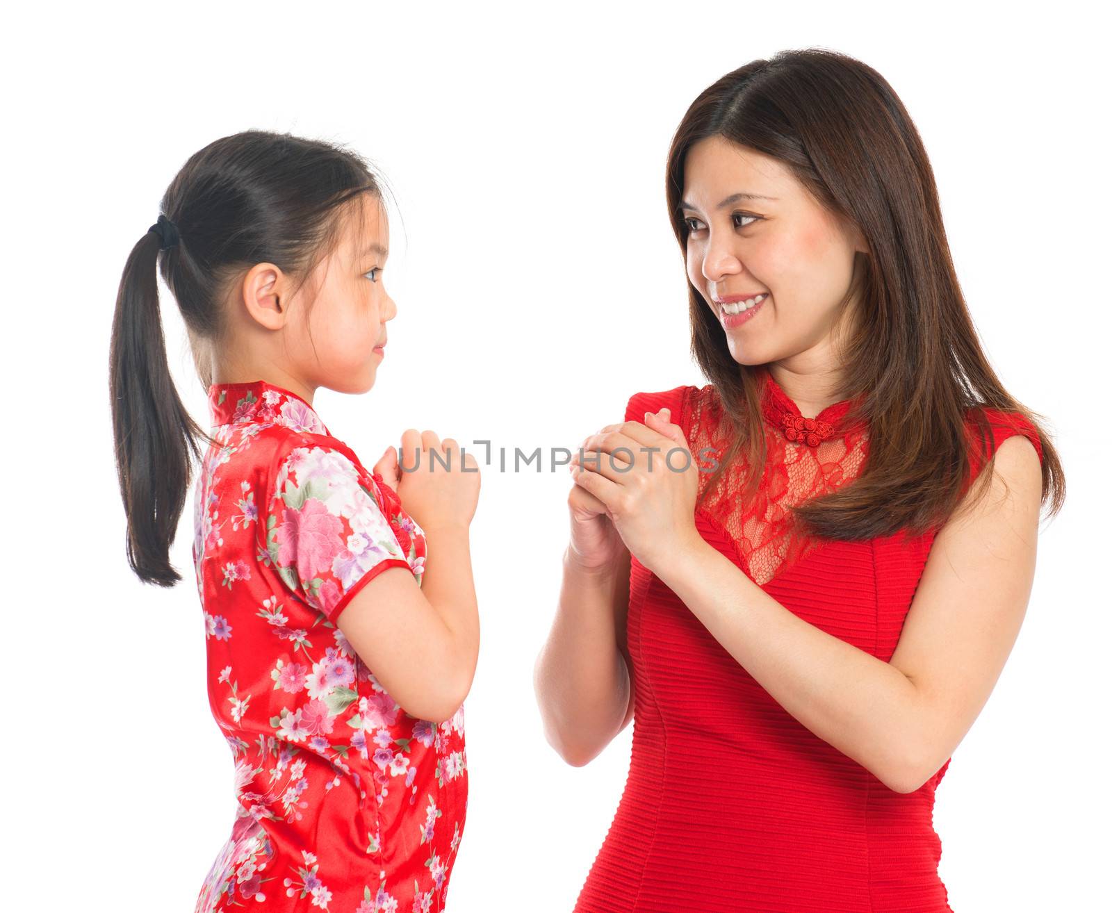Happy Chinese New Year! Chinese parent and child in traditional Chinese cheongsam greeting to each other, isolated on white background