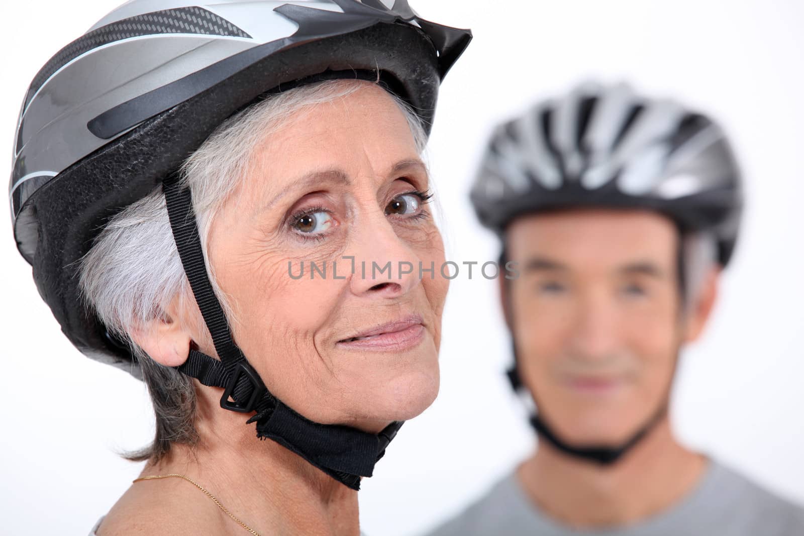 Older couple wearing cycling helmets by phovoir