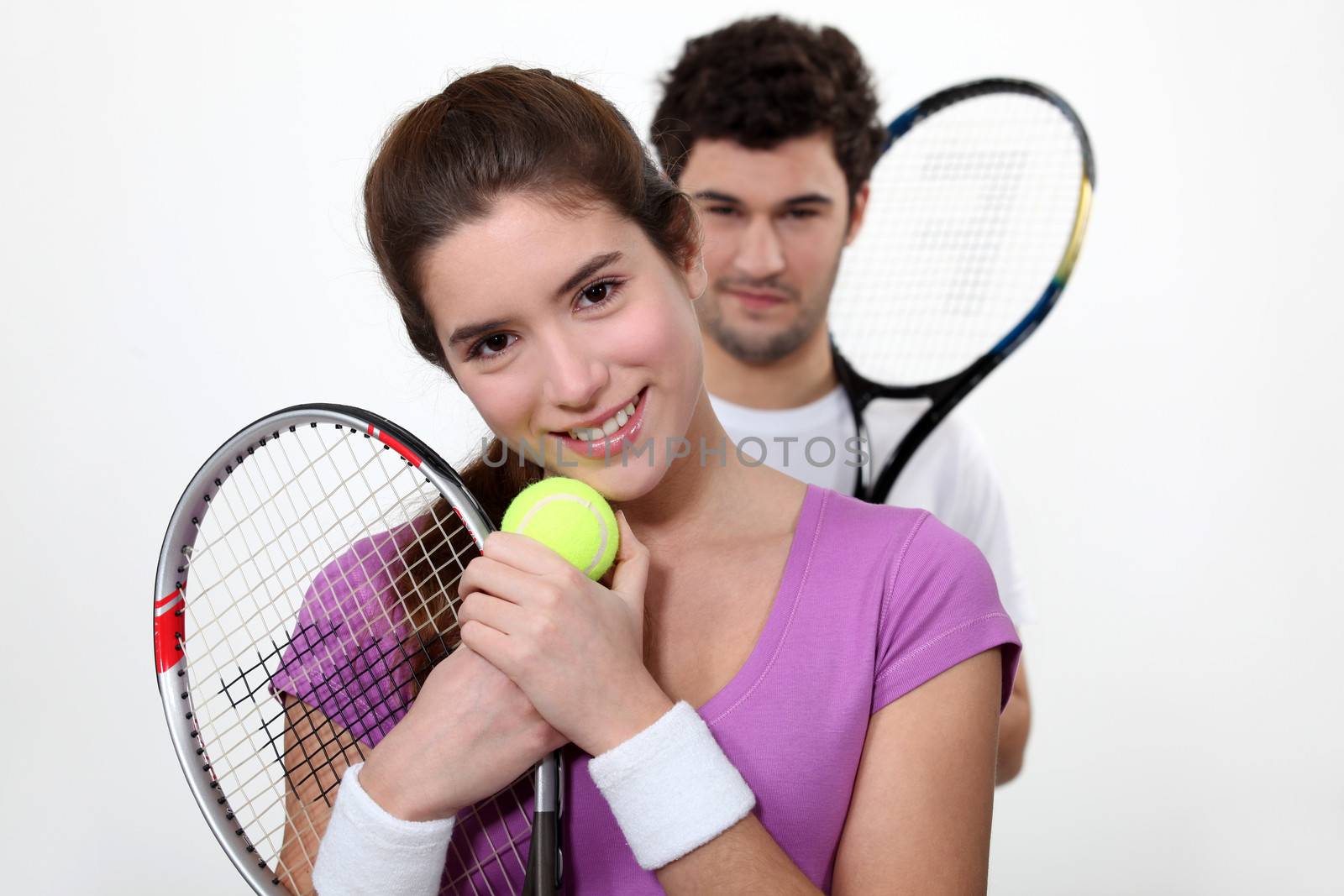 Young couple with tennis racquets by phovoir
