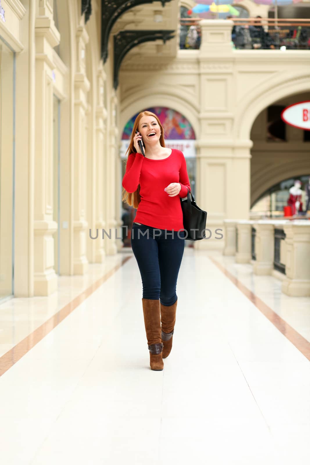 Happy young woman walking in the shop by andersonrise