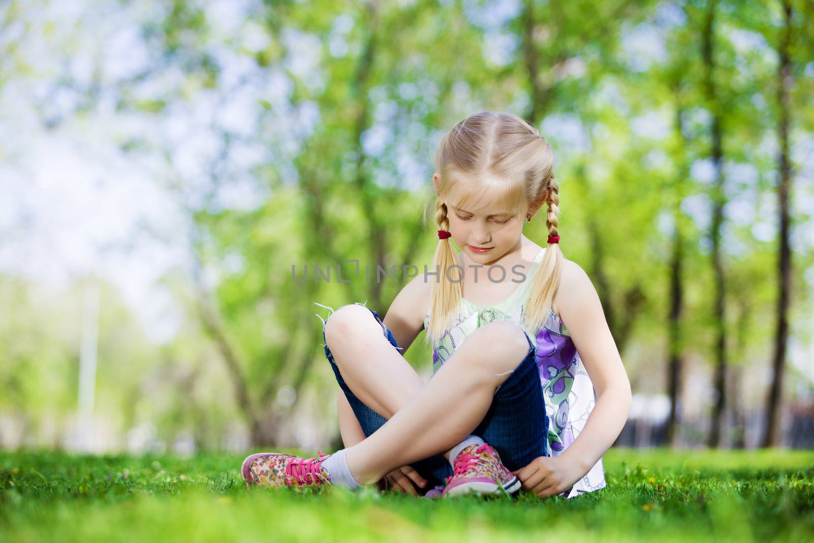 Image of little cute girl sitting on grass in park