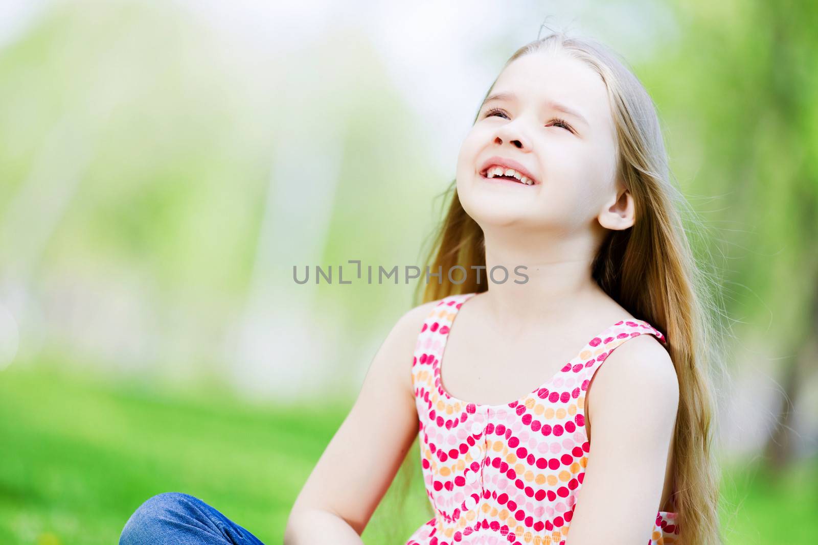 Image of little cute girl sitting on grass in park