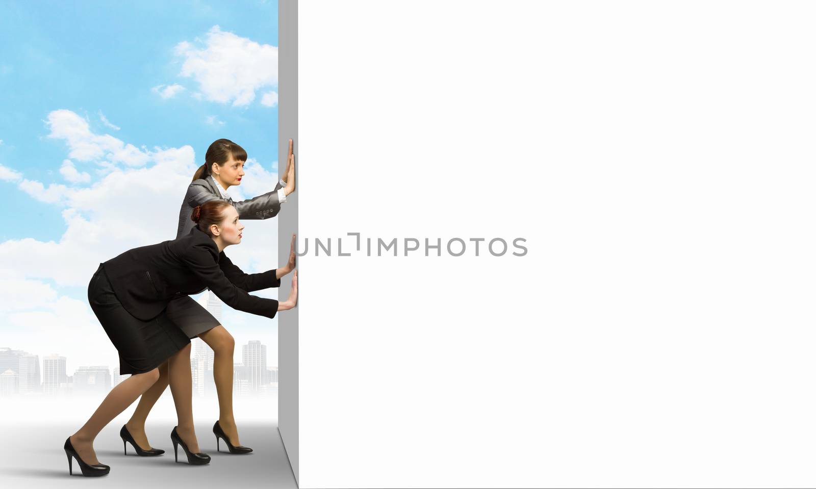 Image of two businesswomen pushing blank wall. Place for text