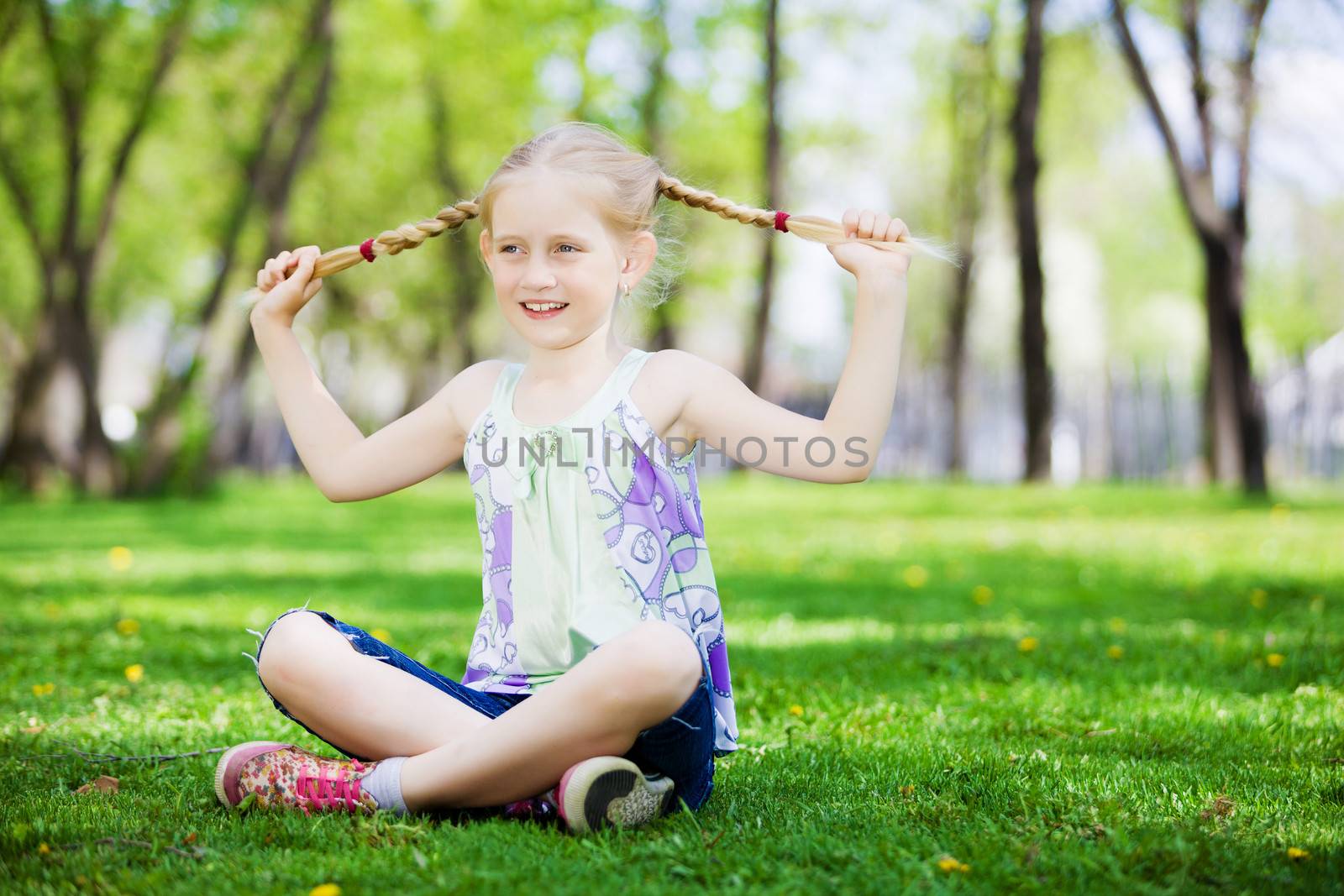 Image of little cute girl sitting on grass in park