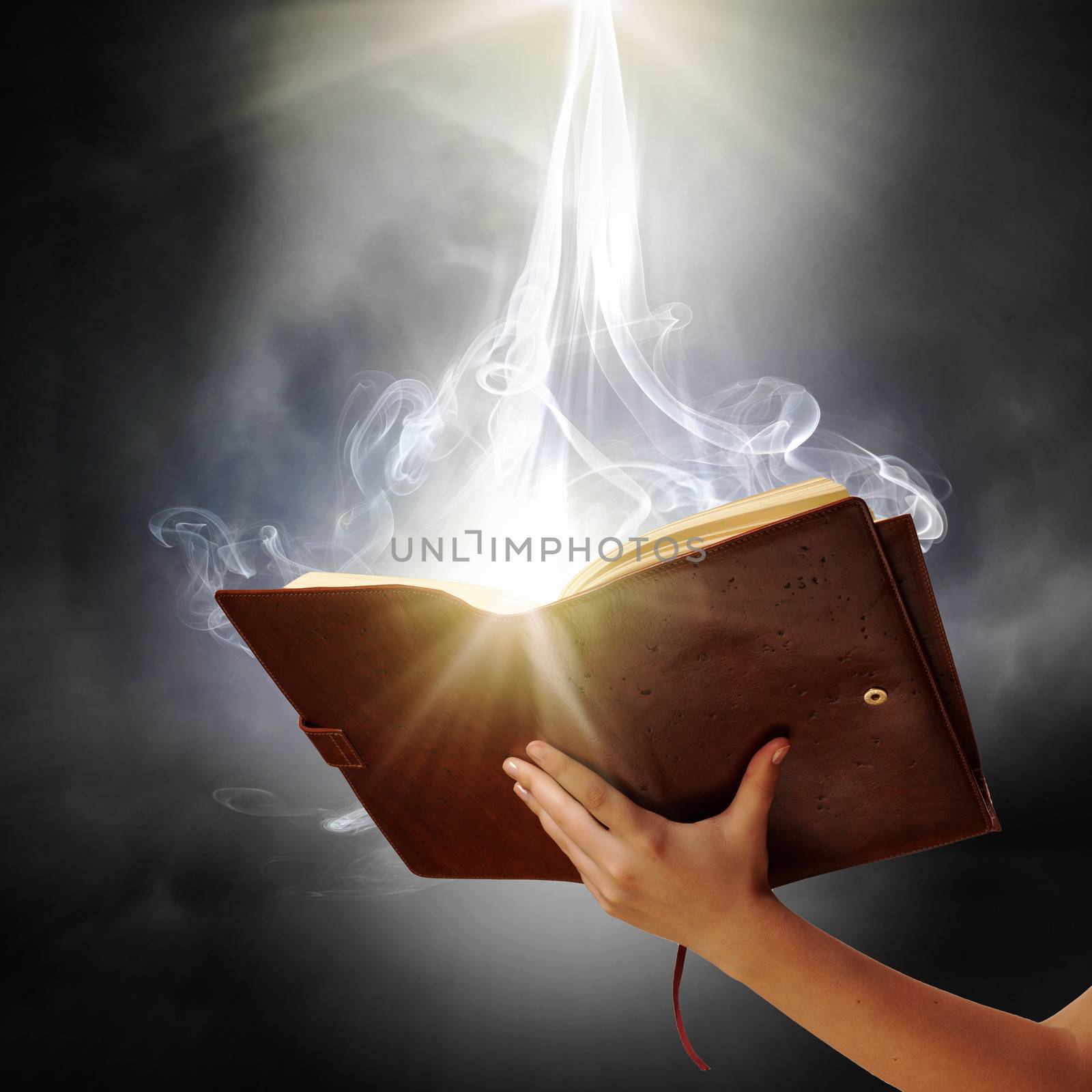 Human hand holding magic book with magic lights