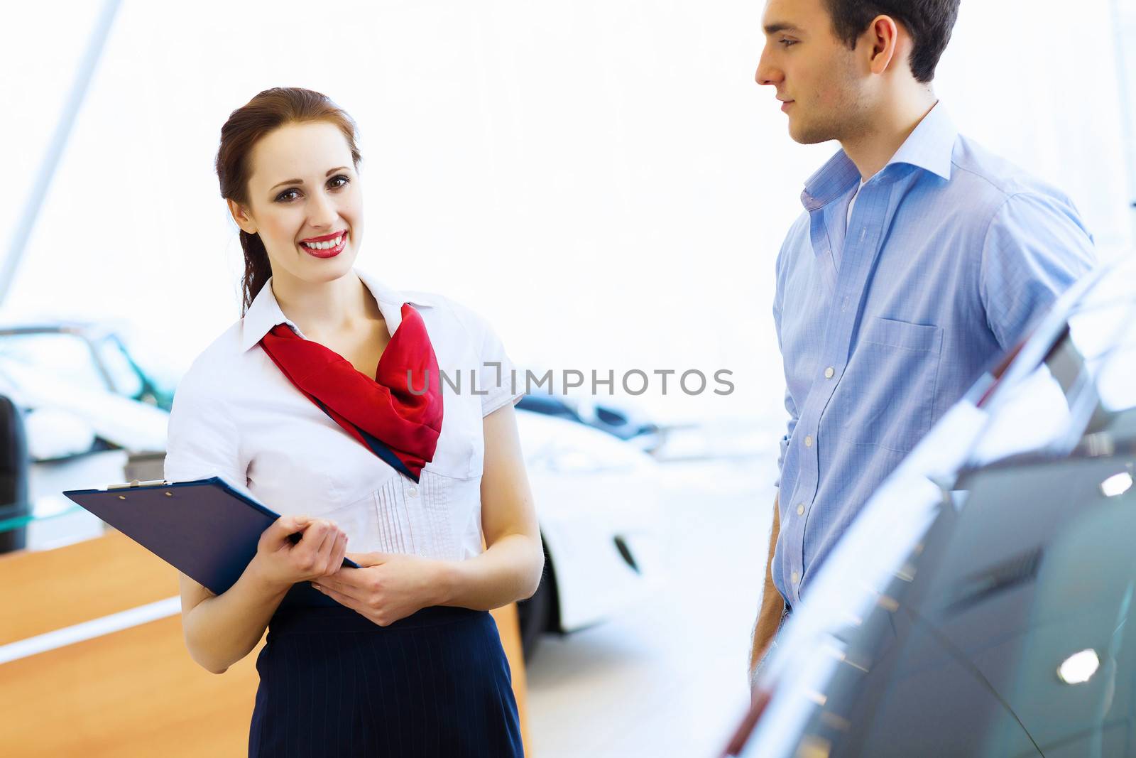 Young man choosing car at salon with help of consultant