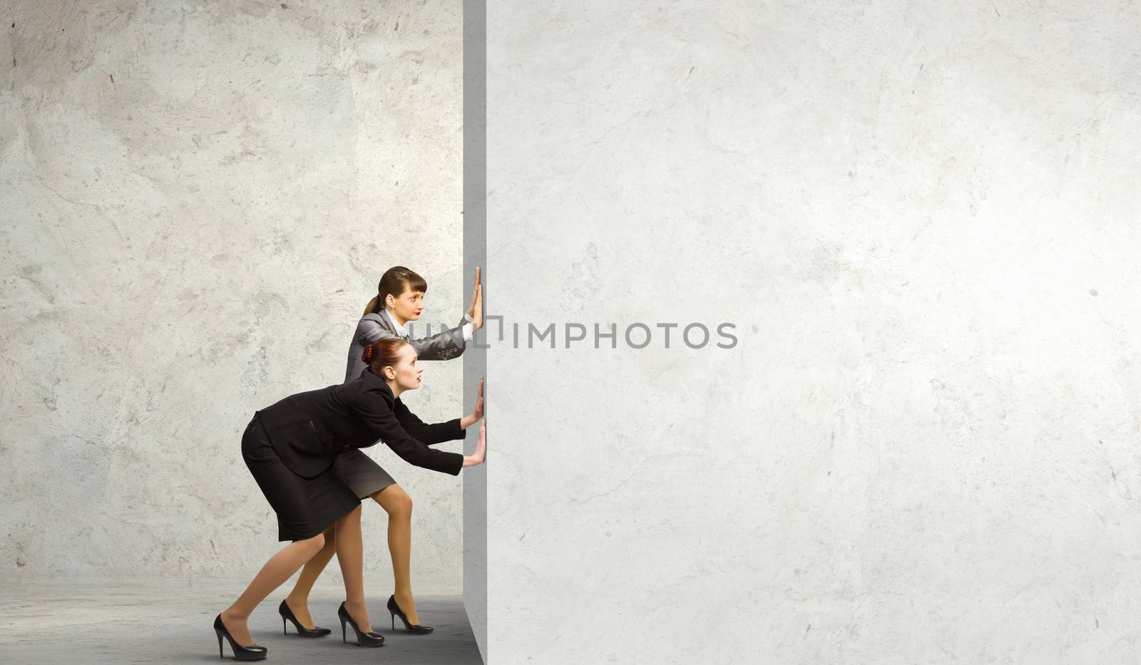 Two businesswoman pushing blank wall. Place for text