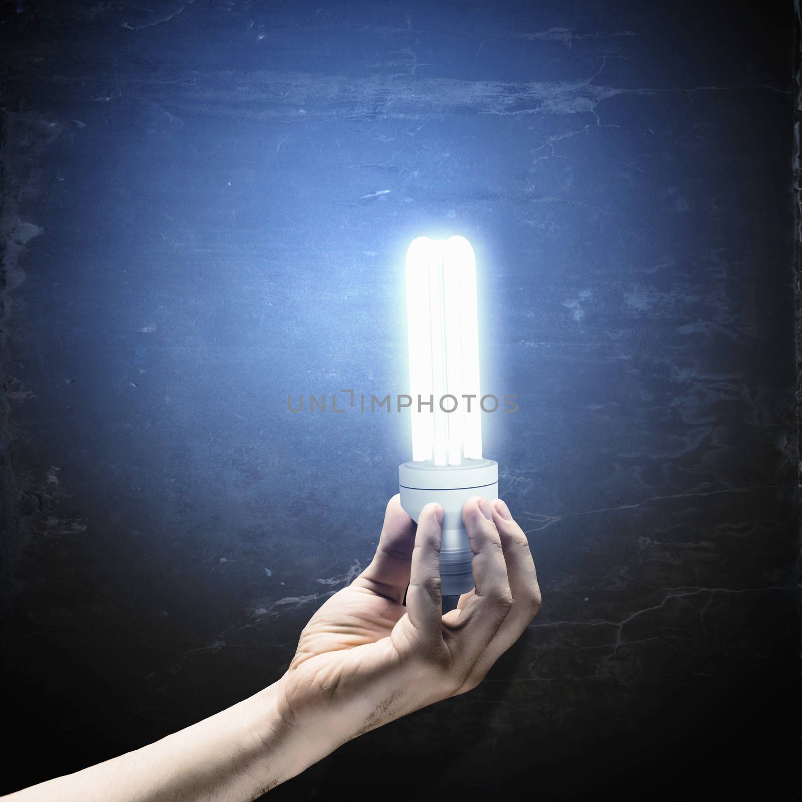 Close up image of human hand holding electrical bulb in darkness