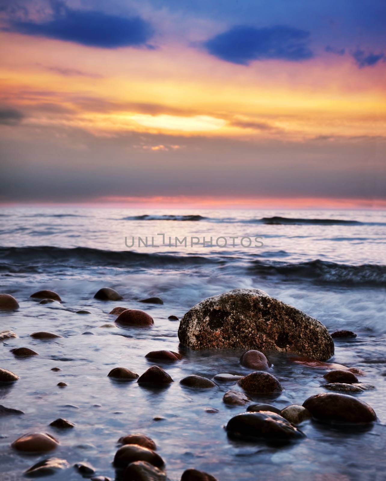 Dramatic colorful sunrise on a rocky beach. Baltic sea