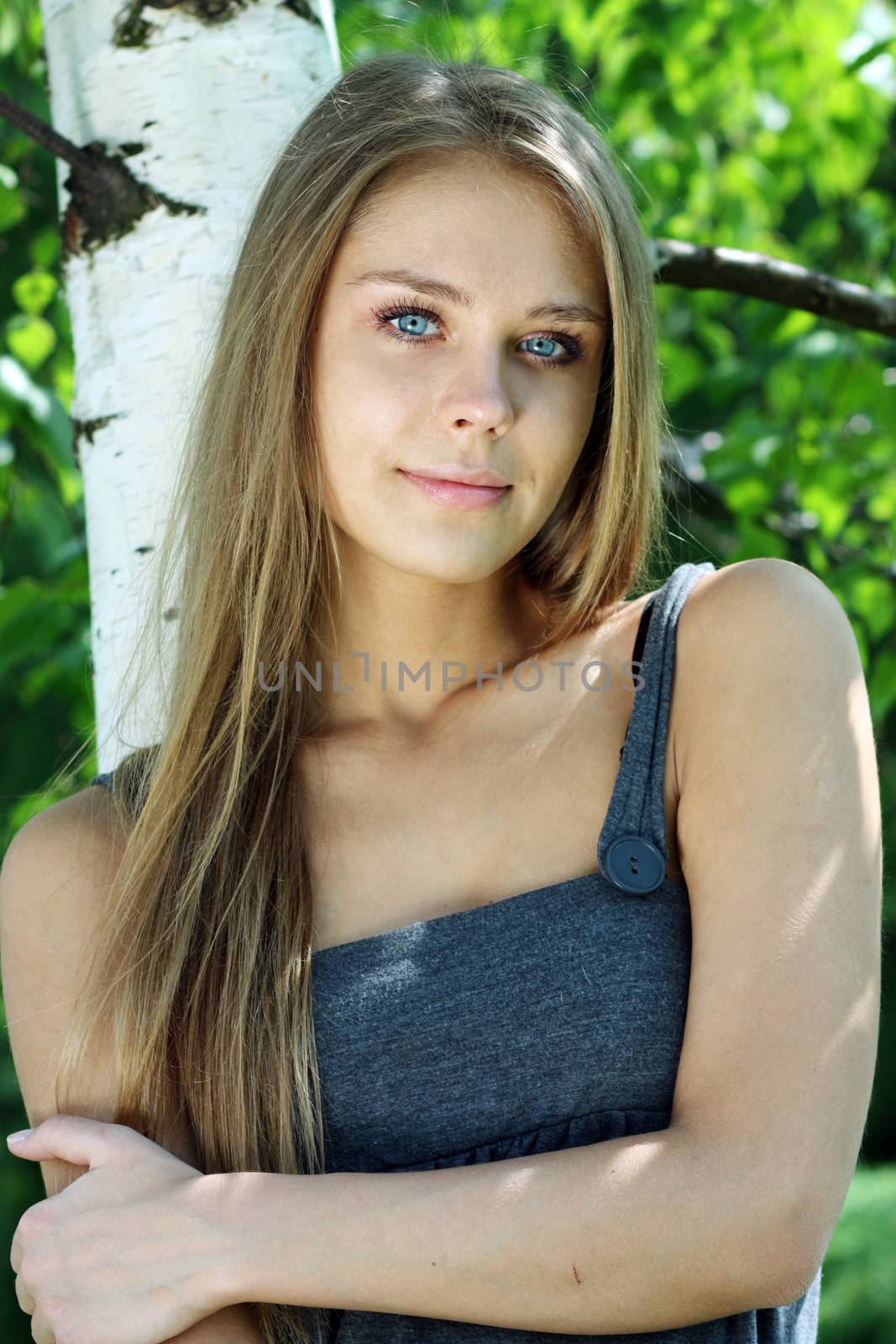 Portrait of the young beautiful woman on a background of leaves of a birch