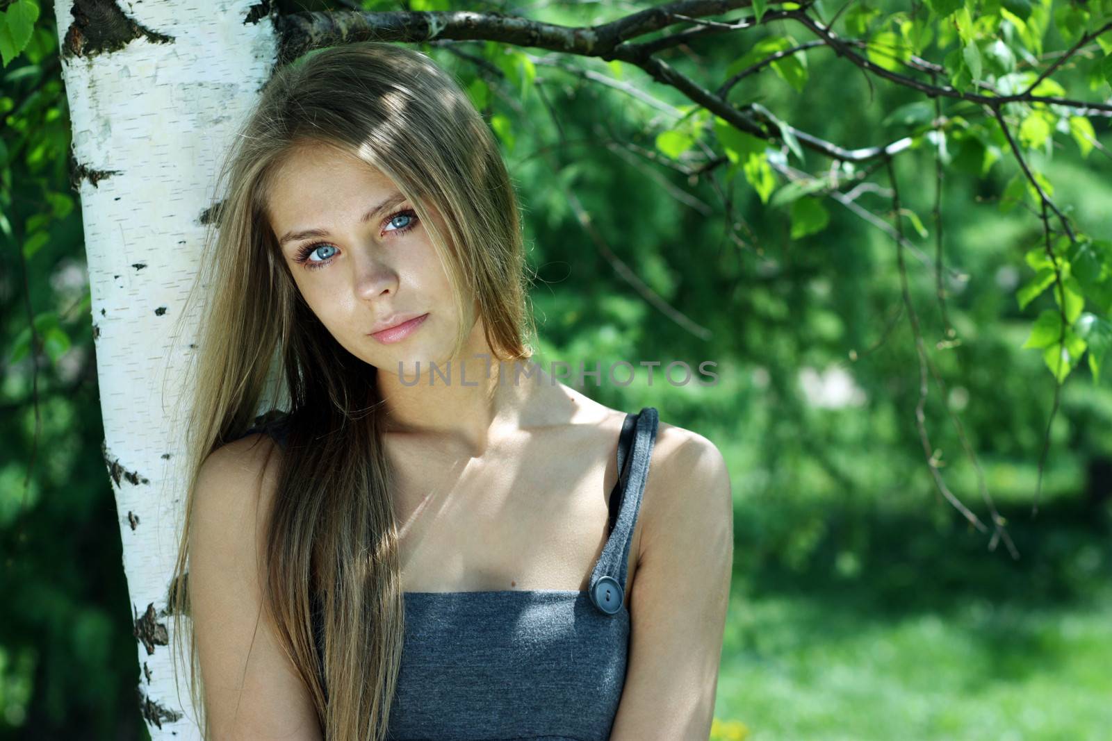 Portrait of the young beautiful woman on a background of leaves of a birch